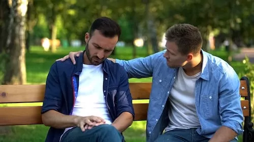 Young male supporting friend sitting outdoors together, friendship care, advice
