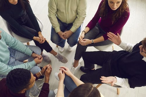 Diverse people listening to therapist, sitting in circle in group therapy session